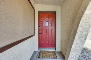 A red door with intricate designs, a doormat with 'Welcome' text, and a textured wall. - Bullhead City Home - Near Colorado River! (Bullhead City)