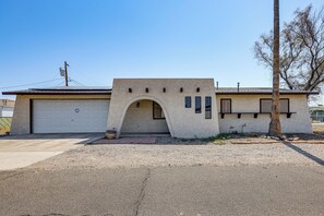 A single-story building with a garage, an arched entryway, and a small porch area. - Bullhead City Home - Near Colorado River! (Bullhead City)