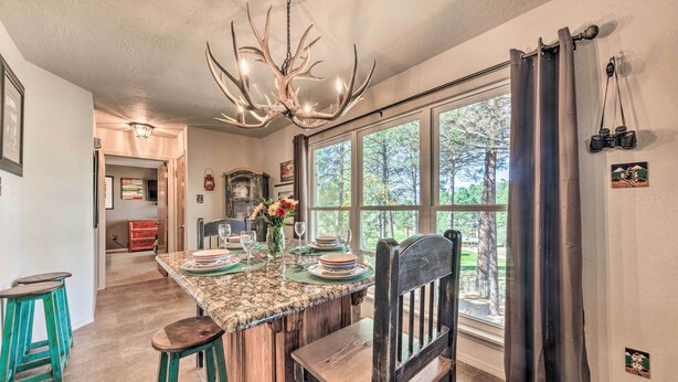 A kitchen with a large island, wooden chairs, and a chandelier. - Ruidoso Getaway w/ Deck, Golf Course Views! (Ruidoso)