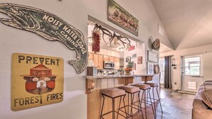 A kitchen with wooden cabinets, a microwave, and a bar area with stools. - Ruidoso Getaway w/ Deck, Golf Course Views! (Ruidoso)