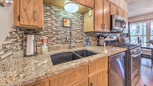 A kitchen with granite countertops, wooden cabinets, a stainless steel stove, and a microwave. - Ruidoso Getaway w/ Deck, Golf Course Views! (Ruidoso)