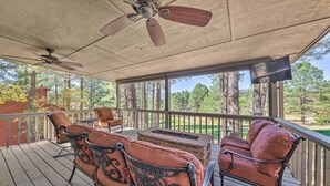 A covered outdoor seating area with a ceiling fan, a flat-screen TV, and a view of a golf course. - Ruidoso Getaway w/ Deck, Golf Course Views! (Ruidoso)