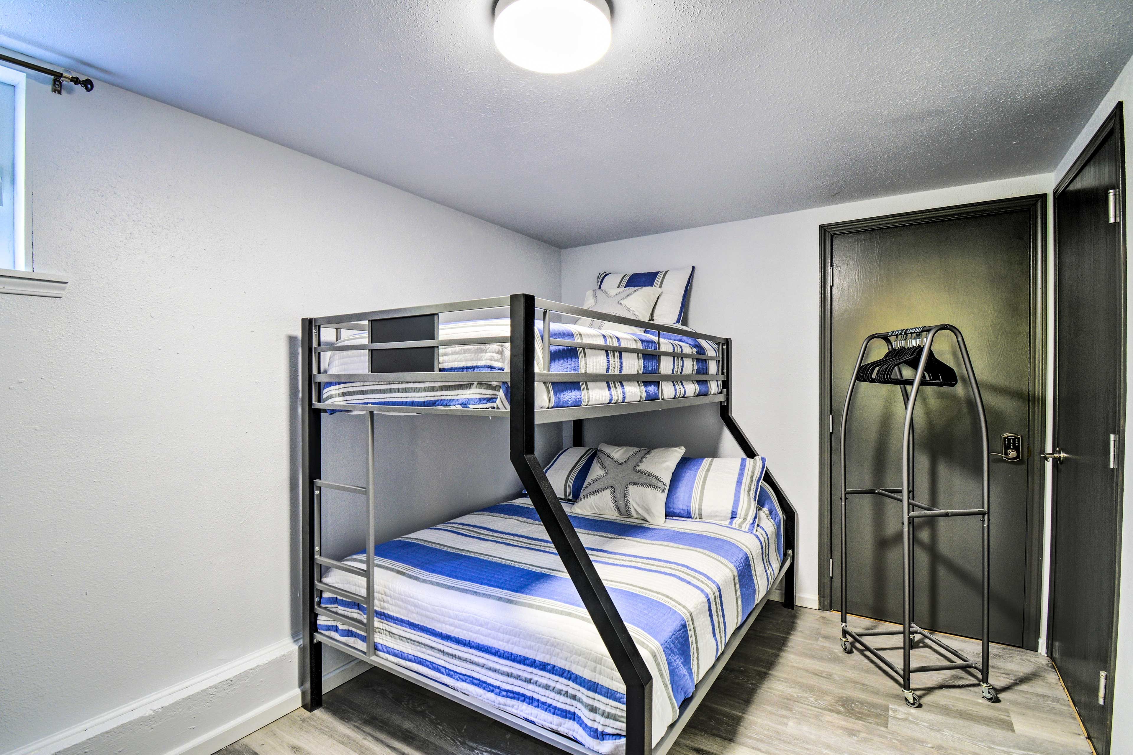A bunk bed with striped bedding in a room with a door and a coat rack.