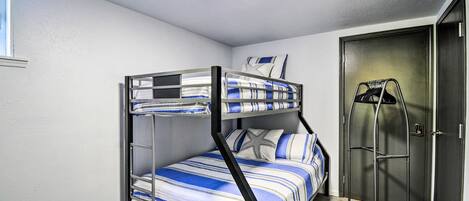 A bunk bed with striped bedding in a room with a door and a coat rack.