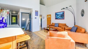 Uma sala de estar moderna com sofá, mesa de centro e área de jantar com mesa de madeira e banquetas.