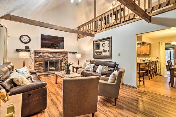 Relax in a spacious living area with a high ceiling, leather sofa, and brick fireplace.