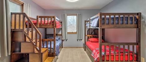 A room with bunk beds, a carpeted floor, and a window with curtains.