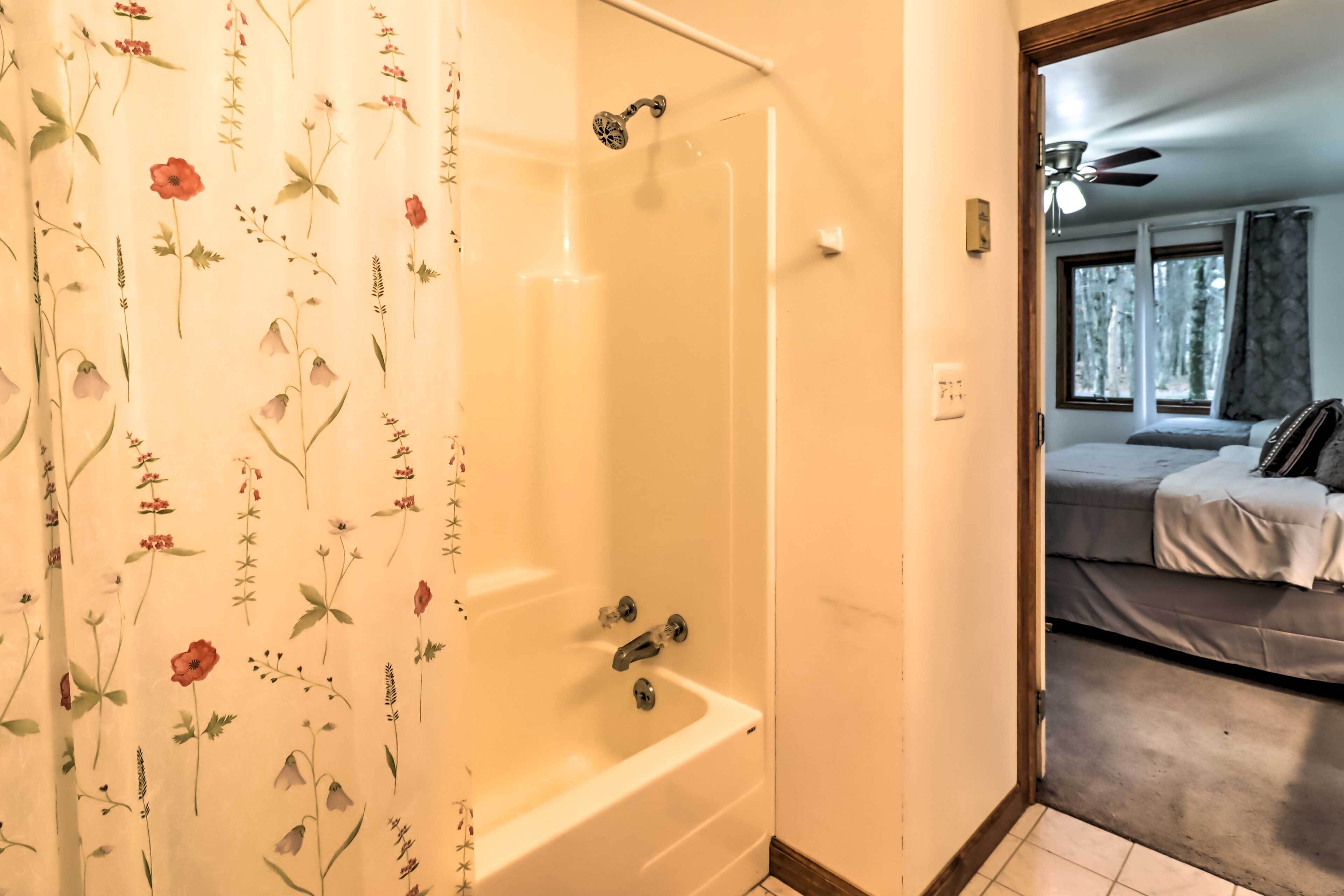Une salle de bain avec une douche, une baignoire et une fenêtre avec des rideaux.