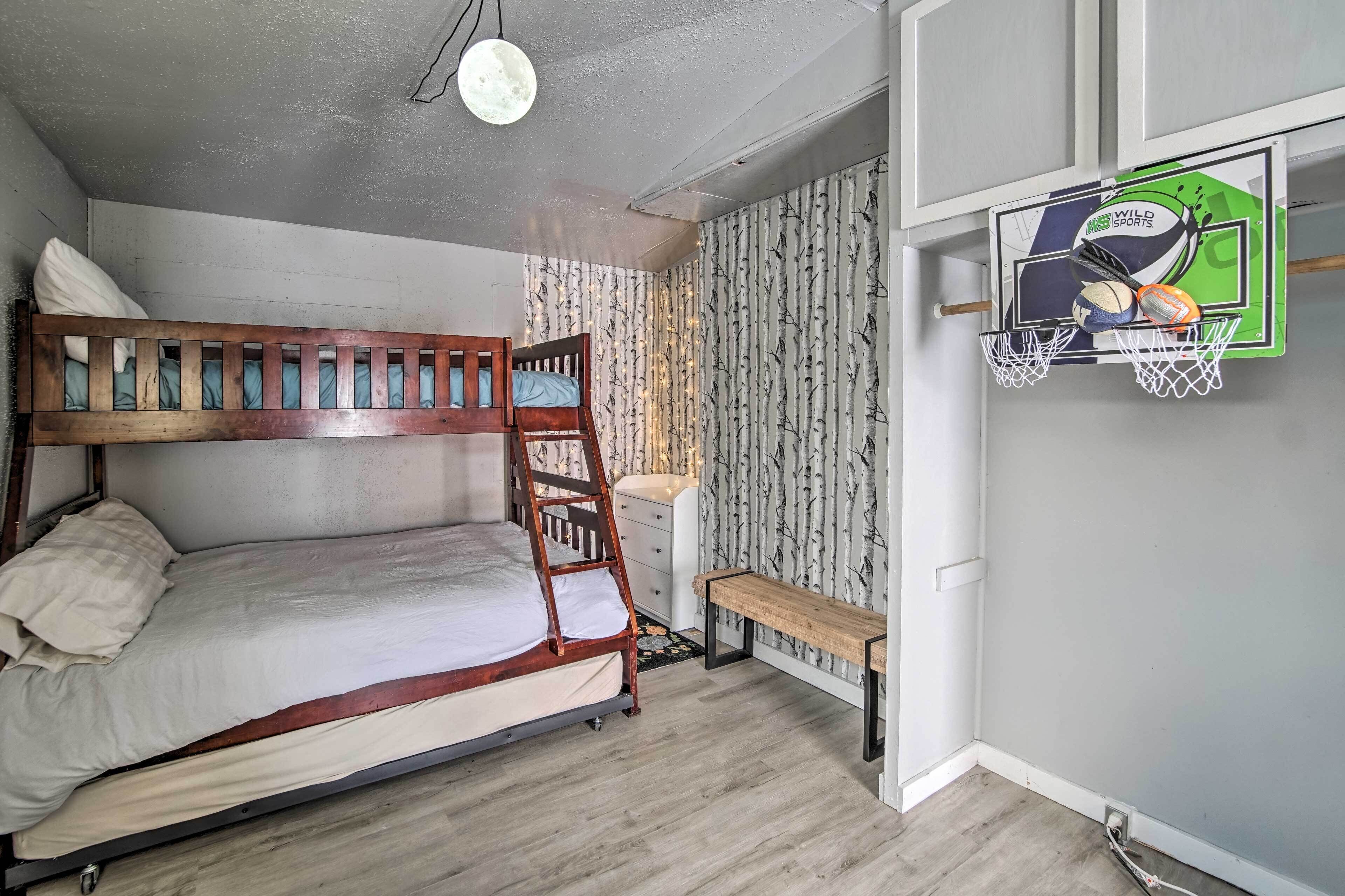 A bunk bed with a ladder, a bench, a basketball hoop, and a wall with a patterned wallpaper.