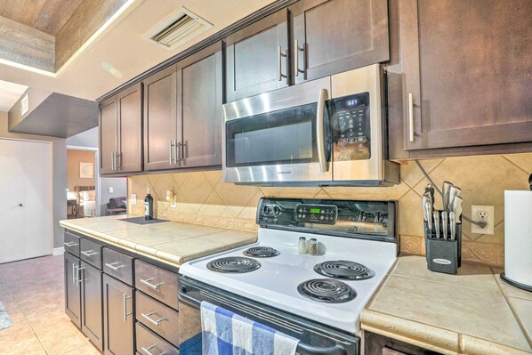 A modern kitchen with stainless steel appliances, dark wooden cabinets, and a tiled backsplash.