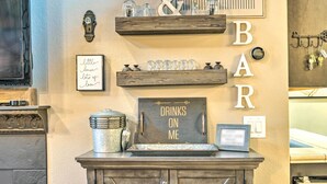 A bar area with shelves holding glasses and a sign that reads "Drinks on me." - Peoria Oasis w/ Resort Amenities, 2 Mi to Downtown (Peoria)