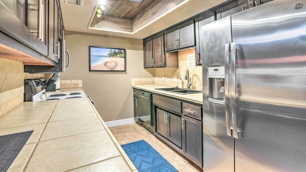 A modern kitchen with stainless steel appliances, a built-in oven, and a large island with a black rug. - Peoria Oasis w/ Resort Amenities, 2 Mi to Downtown (Peoria)