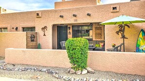 A building with a textured facade, a palm tree, and a surfboard. - Peoria Oasis w/ Resort Amenities, 2 Mi to Downtown (Peoria)
