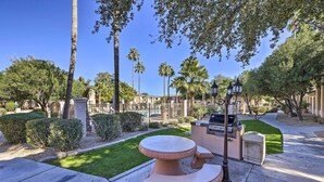 An outdoor patio area with a round table and benches, surrounded by palm trees and a well-maintained lawn. - Dog-friendly Condo w/ Pool & Hot Tub in Phoenix (Phoenix)