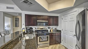 A modern kitchen with dark wood cabinets, stainless steel appliances, and a granite countertop. - Dog-friendly Condo w/ Pool & Hot Tub in Phoenix (Phoenix)