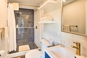 Een moderne badkamer met douche, toilet, wastafel en spiegel.