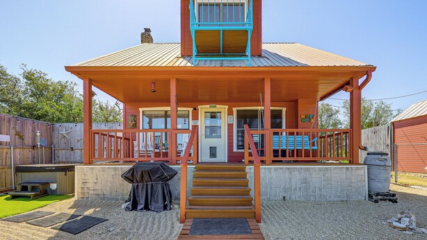 A two-story house with a porch, a front door, and a staircase leading to the entrance. - Pet-friendly Fredericksburg Cabin w/ Hot Tub! (Fredericksburg)