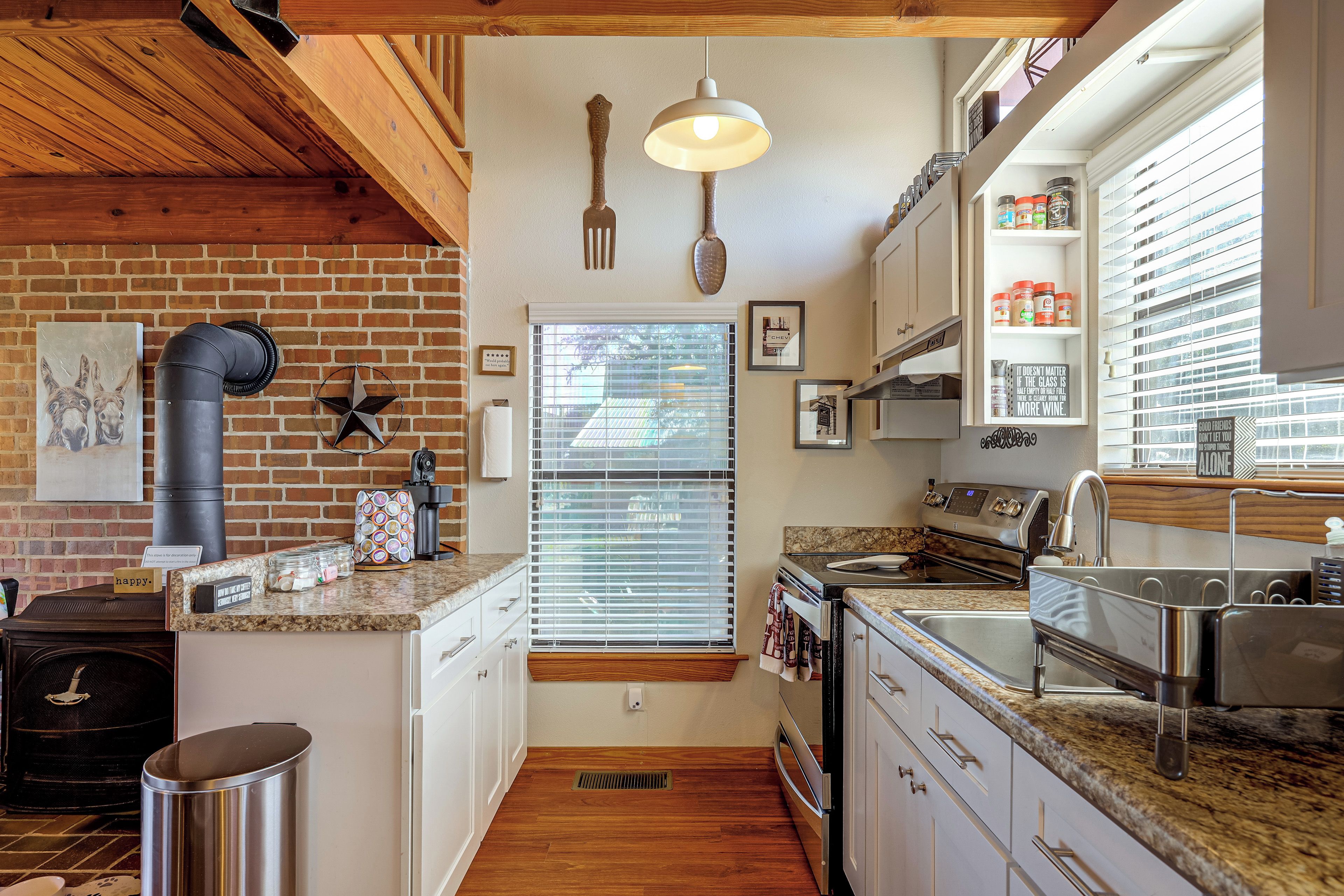 Una cocina con pared de ladrillo, techo de madera y ventana con persianas.