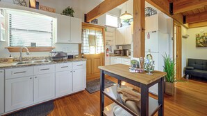A modern kitchen with white cabinets, a wooden dining table, and a built-in oven.