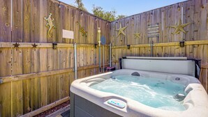 A hot tub with a control panel, surrounded by a wooden fence with star decorations and a sign. - Pet-friendly Fredericksburg Cabin w/ Hot Tub! (Fredericksburg)