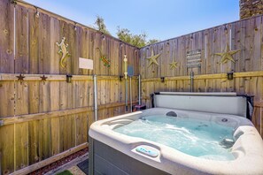 A hot tub with a control panel, surrounded by a wooden fence with star decorations and a sign. - Pet-friendly Fredericksburg Cabin w/ Hot Tub! (Fredericksburg)