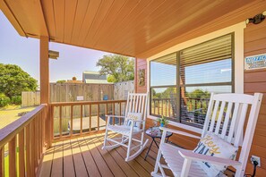 A wooden deck with two rocking chairs and a table, overlooking a fenced yard. - Pet-friendly Fredericksburg Cabin w/ Hot Tub! (Fredericksburg)