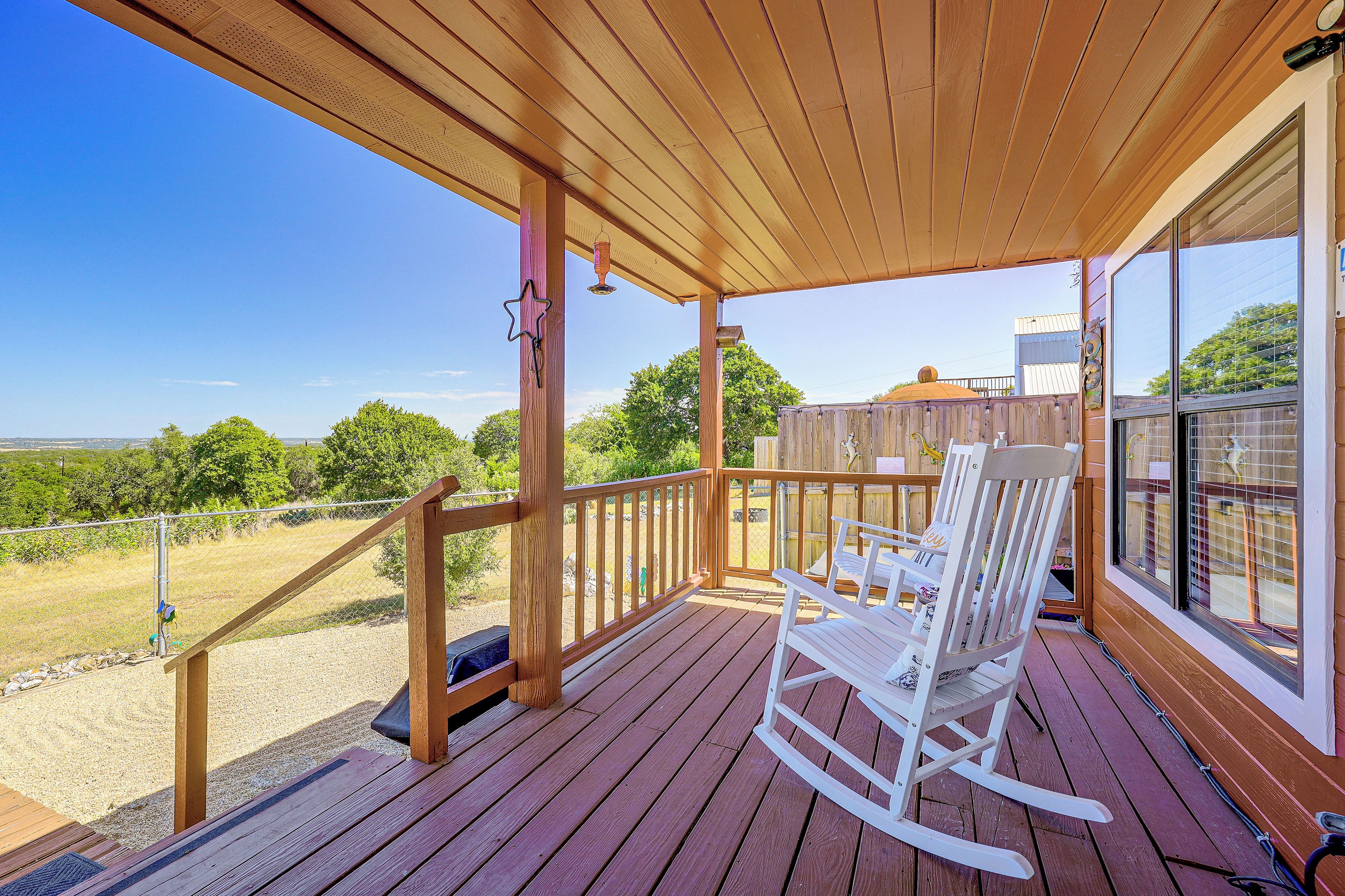 Una terraza de madera con una mecedora y vistas al paisaje.