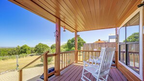 A wooden deck with a rocking chair and a view of the landscape. - Pet-friendly Fredericksburg Cabin w/ Hot Tub! (Fredericksburg)