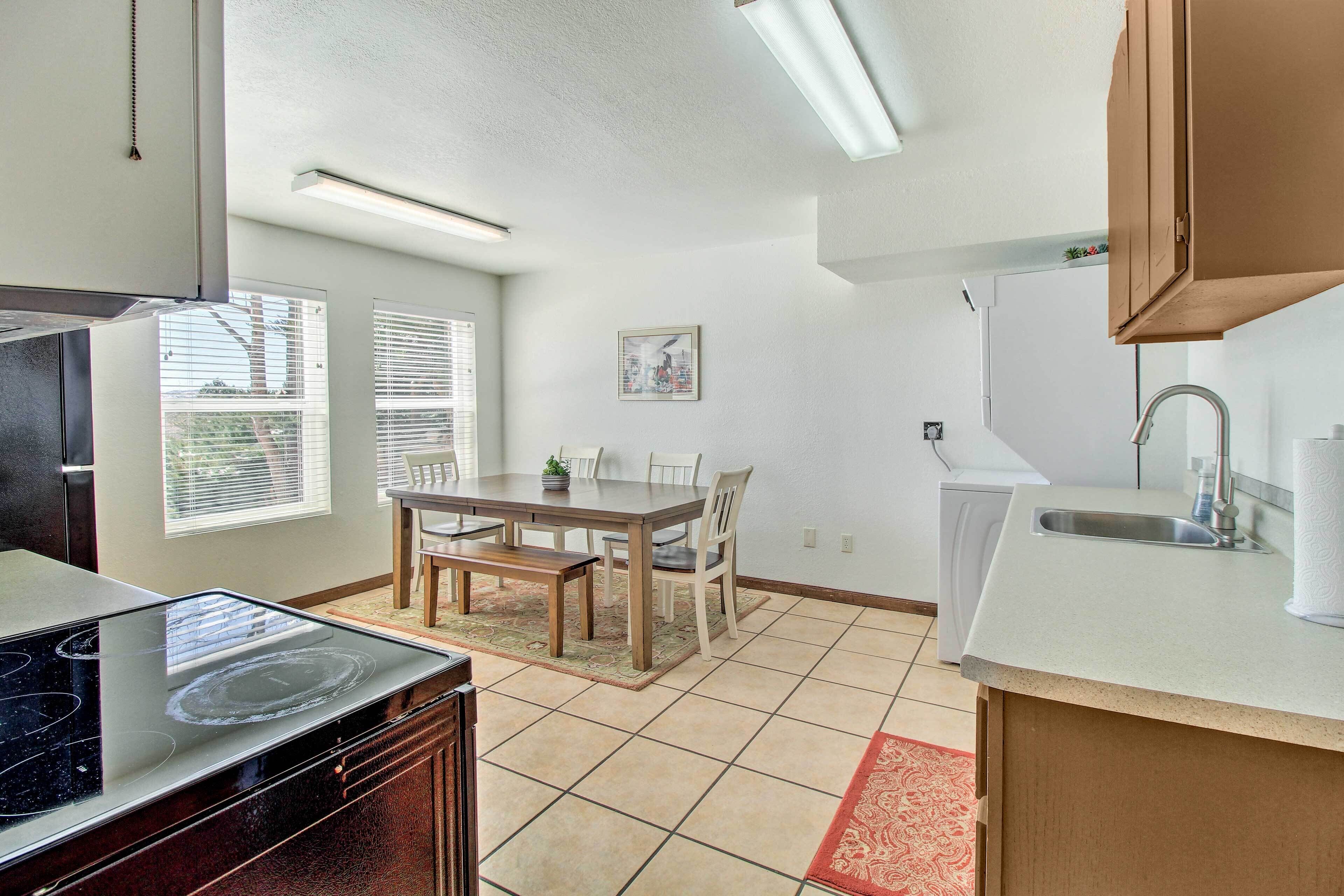 A modern kitchen with a dining area, including a stove, sink, and a table with chairs.