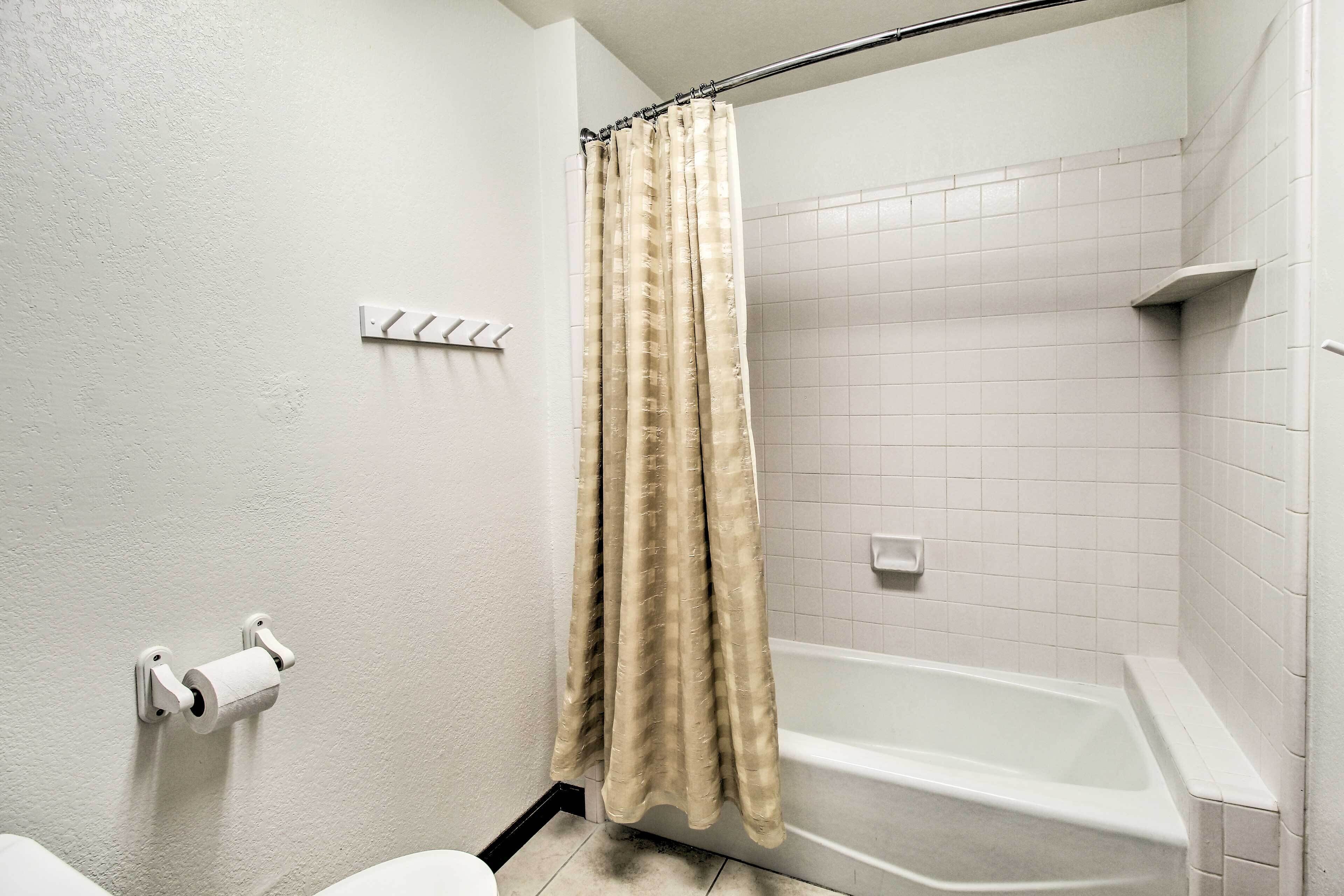 A bathroom with a shower, toilet, and a towel rack.