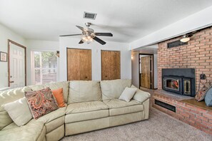 A living room with a beige sectional sofa, a fireplace, and a ceiling fan. - Patio, Grill & Fire Pit: Show Low Escape! (Show Low)