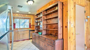 A kitchen with wooden cabinets, a stainless steel refrigerator, and a window with a view.