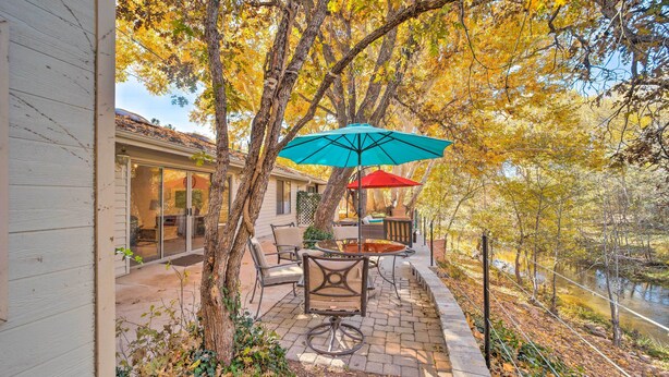 A patio with outdoor furniture, a red umbrella, and a view of a river.