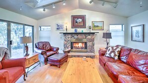A spacious living room with a stone fireplace, leather sofas, and a wooden coffee table.