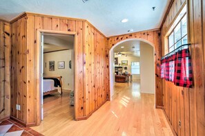 A wooden-paneled hallway with a bed and a dining area in the background. - Beautiful Cabin w/ Deck on East Verde River! (Payson)