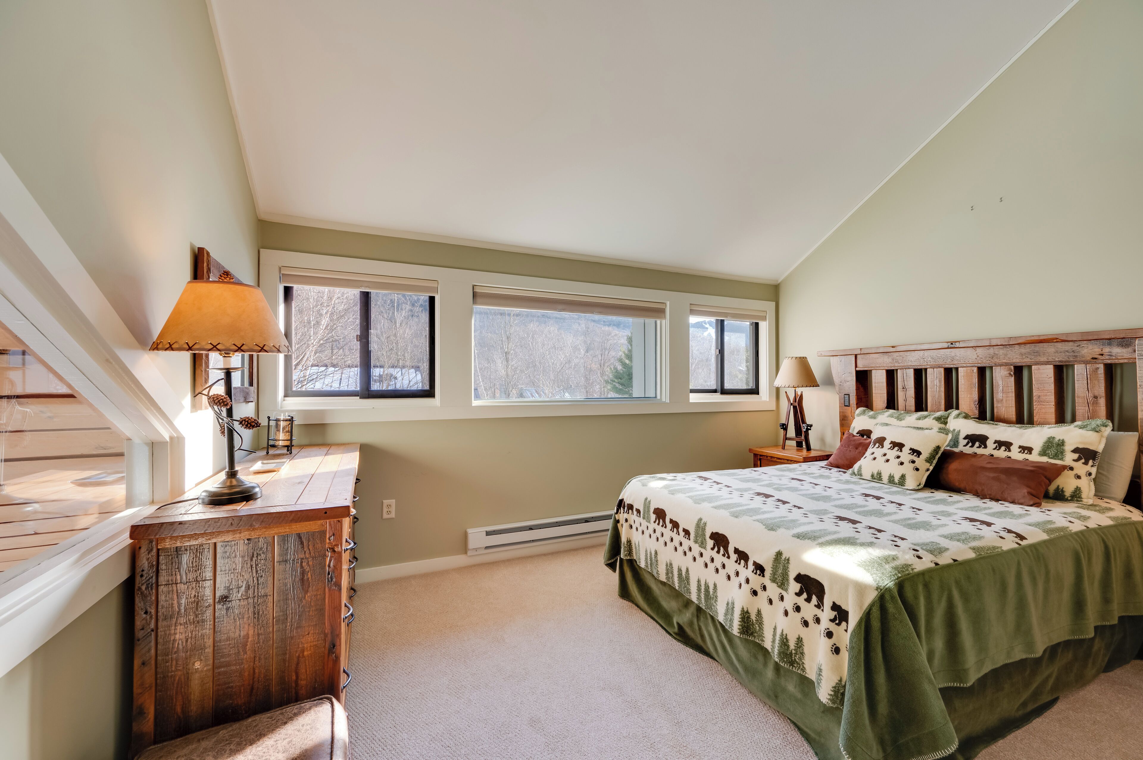 A bedroom with a bed, a nightstand, a lamp, a window, and a radiator.