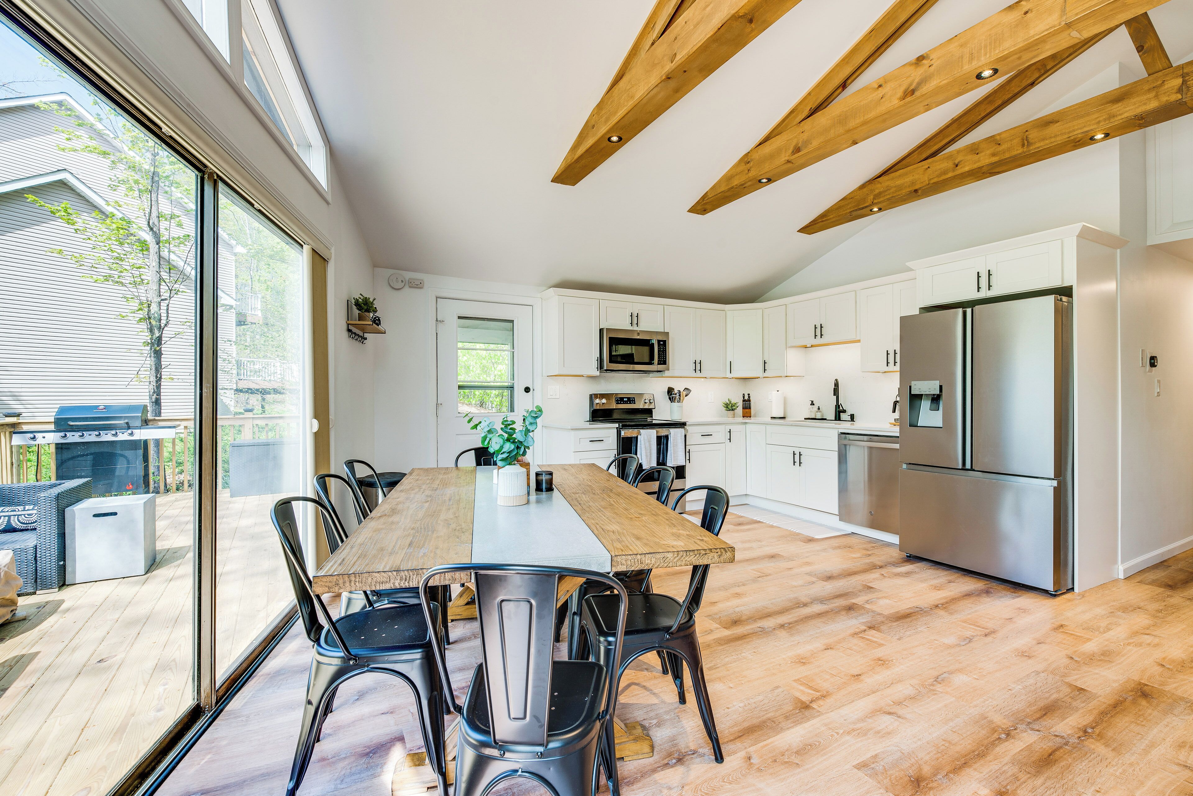 Una cocina moderna con armarios blancos, electrodomésticos de acero inoxidable y una amplia mesa de comedor de madera.