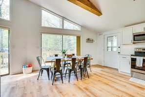 Een ruime keuken met een grote eettafel, witte kasten en een houten plafond.