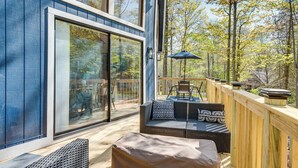 A modern deck with a glass door, outdoor furniture, and a wooden railing. - Deck & Community Perks: Bright Pocono Lake Home! (Pocono Lake)