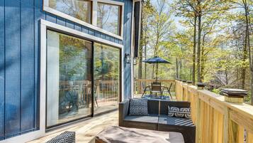 Una terraza moderna con puerta de cristal, mobiliario exterior y barandilla de madera.