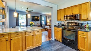 A modern kitchen with wooden cabinets, a large island, stainless steel appliances, and pendant lighting. - Pet-friendly Pensacola Home w/ Sunny Backyard! (Pensacola)