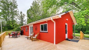 Ein rotes Gebäude mit einer Holzterrasse, einem Grill und Sitzgelegenheiten im Freien.