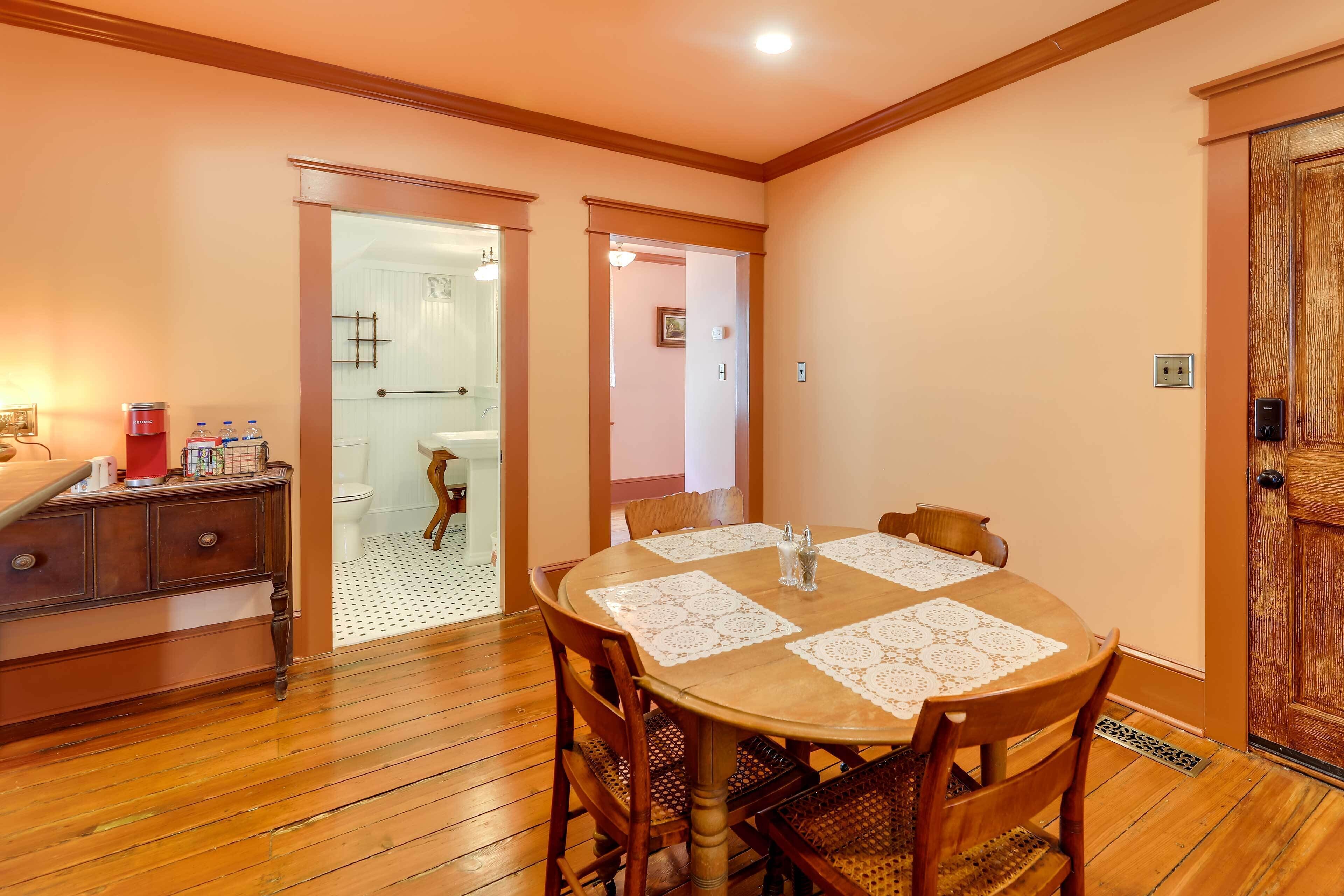 A dining area with a wooden table and chairs, a wooden cabinet, and a door leading to another room.