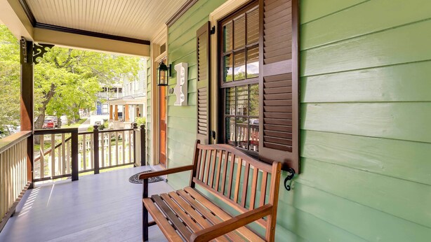 A wooden bench on a porch with a green wall and a window with shutters. - Victorian Vacation Rental Apt in Downtown New Bern (New Bern)