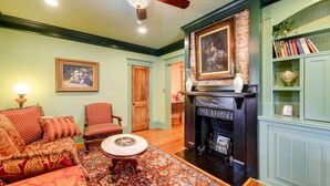 A cozy living room with a fireplace, a sofa, a chair, and a bookshelf. - Victorian Vacation Rental Apt in Downtown New Bern (New Bern)