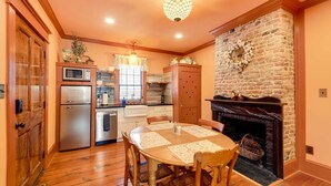 A cozy kitchen with a fireplace, wooden cabinets, and a dining table with chairs. - Victorian Vacation Rental Apt in Downtown New Bern (New Bern)
