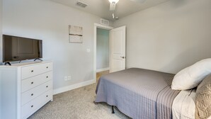 Ein Schlafzimmer mit einem Bett, einem Schminktisch, einem Deckenventilator und einem Fernseher.