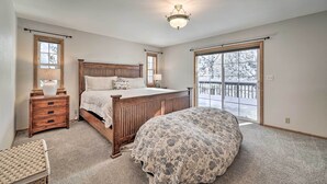 A bedroom with a wooden bed, a nightstand, a lamp, and a view of a snowy deck through a sliding glass door. - Calpine Mountain Retreat w/ High-speed Internet (Calpine)