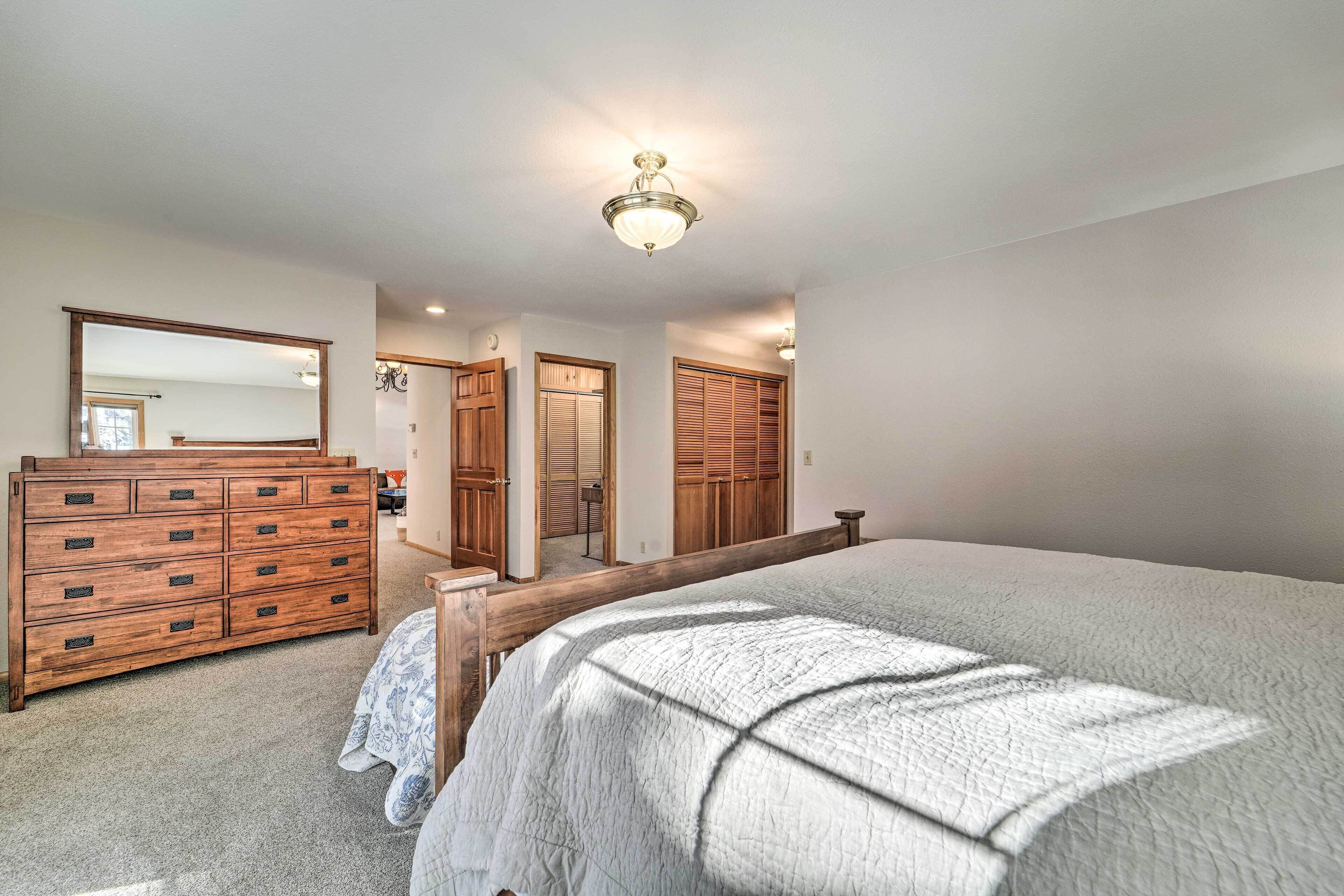 A bedroom with a large bed, wooden dresser, and a mirror.