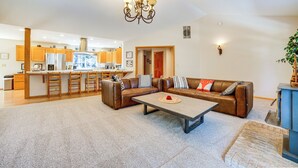 A spacious living area with a brown leather sofa, a coffee table, and a kitchen in the background. - Calpine Mountain Retreat w/ High-speed Internet (Calpine)